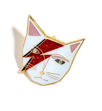 A Blue Dog Posters Kitty Stardust Enamel Pin shaped like a cat's face with a design resembling David Bowie's iconic lightning bolt makeup. The cat's face is outlined in gold with features detailed in red, white, and blue, reminiscent of a Nia Gould caricature.