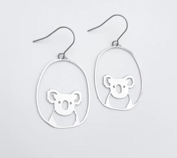 Introducing the Denz Mini Earrings Koalas Silver by Blue Dog Posters: a pair of lightweight silver drop earrings showcasing a minimalist Midi Koala bear design within an oval hoop. Crafted from recycled stainless steel, these earrings feature hook-style backings for easy wear.