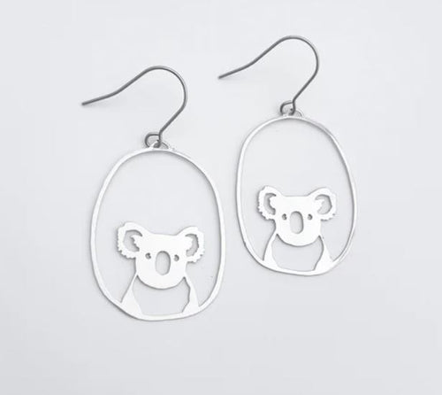 Introducing the Denz Mini Earrings Koalas Silver by Blue Dog Posters: a pair of lightweight silver drop earrings showcasing a minimalist Midi Koala bear design within an oval hoop. Crafted from recycled stainless steel, these earrings feature hook-style backings for easy wear.