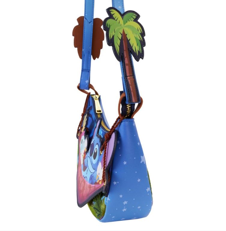 The Lilo & Stitch Camping Cuties Crossbody Bag by Blue Dog Posters is a blue handbag decorated with a character that has large eyes and blue fur. The design includes tropical-themed elements such as palm trees and stars. The bag features a top zipper and a strap adorned with colorful palm tree shapes.