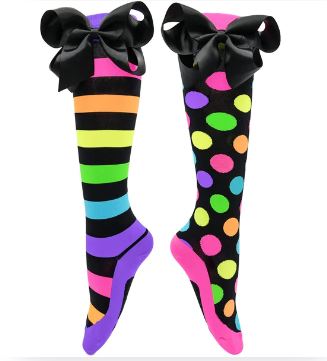 The Madmia Liquorice Bows Socks by Blue Dog Posters showcase large black bows at the top. The left sock highlights vibrant black and colorful stripes, while the right one displays playful colorful polka dots. Both socks have bright pink soles and accents, making them a quirky addition to any outfit.
