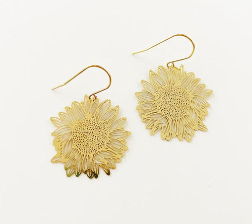 The Denz Mini Earrings Sunflowers Gold by Blue Dog Posters are a pair of gold sunflower dangles intricately designed to resemble sunflowers. The delicate detailing of the petals and the center of the flowers enhances their elegant appearance. These lightweight earrings come with hook attachments for easy wearing and are displayed on a plain white background.