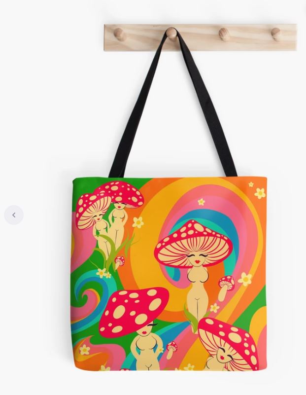 A colorful Mushroom Ladies Tote Bag from Blue Dog Posters hangs on a wooden wall hook. The sublimation printed design showcases vibrant, psychedelic swirls in shades of orange, yellow, green, and purple. The main pattern features whimsical, nude characters with large mushroom caps for heads.