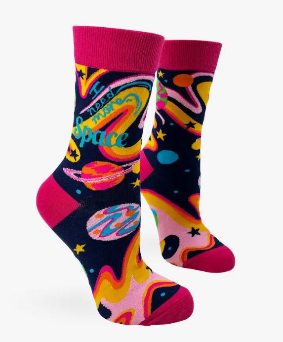 The "I Need More Space Socks Ladies" by Blue Dog Posters are a pair of colorful novelty crew socks featuring a space theme design. These comfortable socks showcase images of planets, stars, and vibrant abstract patterns in shades of pink, yellow, orange, blue, and green. They come with pink cuffs, heels, and toes and are machine wash friendly for easy care.