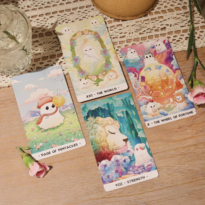 Four Orchid Valley Tarot Cards from Blue Dog Posters featuring animal illustrations are displayed on a lace tablecloth beside two pink flowers and a glass of water. The cards shown: Page of Pentacles, The World, Wheel of Fortune, and Strength.