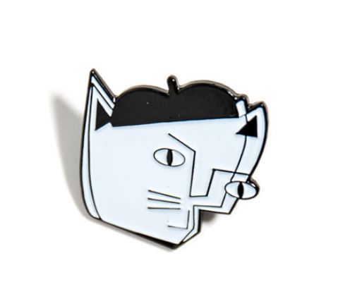 A small Pablo Picatso Enamel Pin by Blue Dog Posters features a minimalist design of a cat’s head with geometric shapes. The cat's ears are pointy, eyes are round with thin pupils, and there are triangular details on its face. The pin uses black and white colors. White background.
