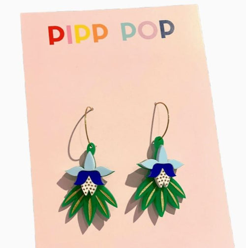 A pair of Dancing Blooms Green Navy Earrings, shaped like flowers with green leaves and blue petals, displayed on a card labeled "Blue Dog Posters.