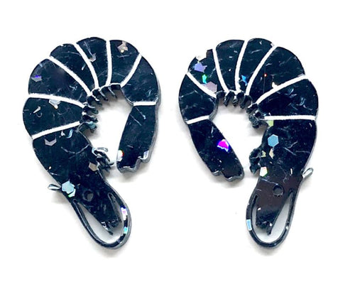 The Prawn Stud Earrings Black Glitter by Blue Dog Posters feature a shrimp design with a shiny, reflective finish and white line details that mimic the segments of a shrimp’s body. Handmade in Melbourne, each black earring includes a hook for fastening.