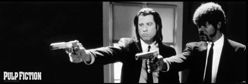 In this Blue Dog Posters’ "Pulp Fiction - Guns GIANT" poster, two men in black suits are pointing guns in the same direction, looking serious and focused. The man on the left has long hair, while the man on the right has curly hair. A window can be seen in the background, with "Pulp Fiction" written at the bottom left corner.