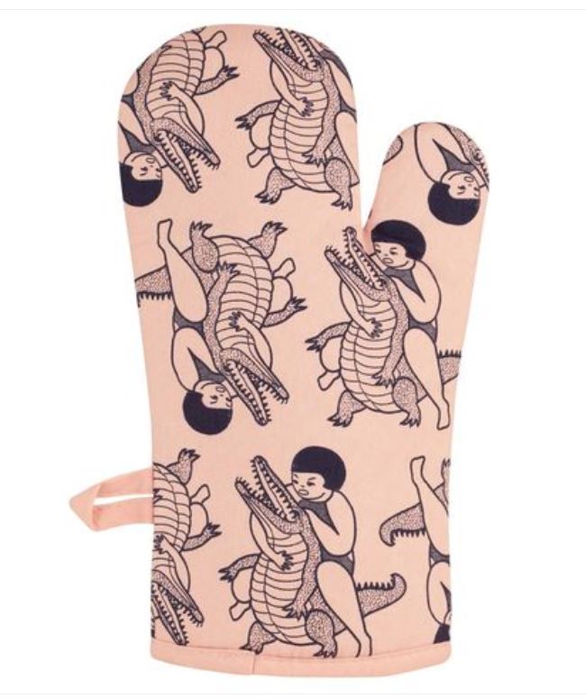 The super-insulated "Scares Your Family" oven mitt from Blue Dog Posters features a pink design with a repeating pattern of an individual wrestling an alligator. The dark ink illustration depicts the person in various poses holding the alligator's head or body. This mitt also includes a convenient loop for hanging.