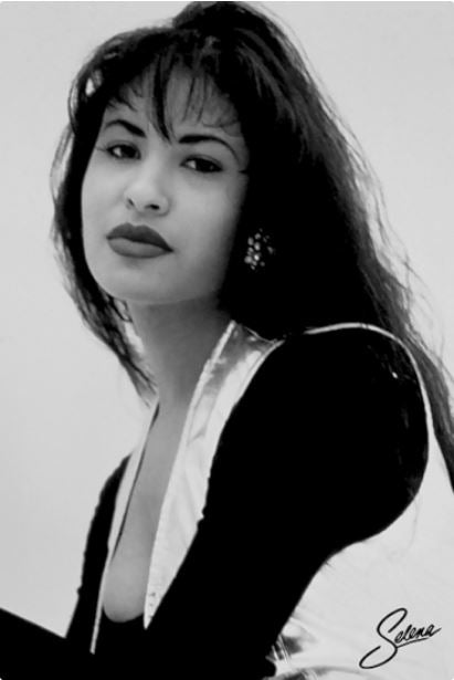 The "Selena Quintanilla" poster by MUS 256 showcases a striking black and white portrait of a woman with long dark hair and bold lipstick. She is seen wearing a metallic vest over a dark top, embodying the essence of an iconic Latin American image. This artwork is printed on premium 150gsm gloss paper and includes a signature in the bottom right corner.