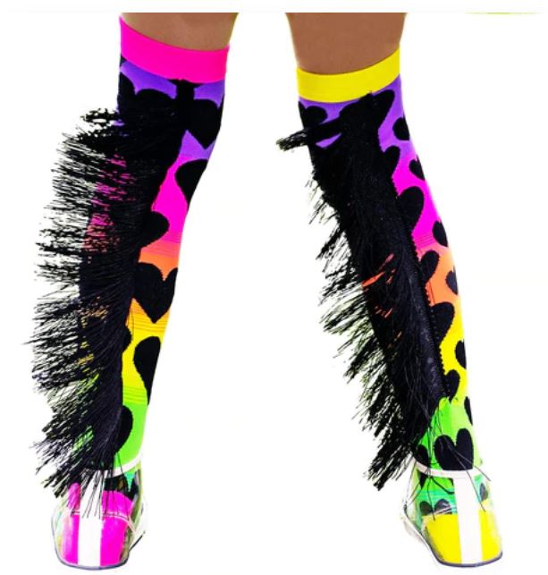 A person slips into the lively Madmia Sunset Socks by Blue Dog Posters, featuring rainbow colors and black heart designs. The fringes flutter as they move in transparent high-heeled shoes. These striking socks are available in one size fits most, bringing a playful flair to any ensemble.