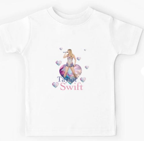 A Blue Dog Posters Kid's T-shirt in white, featuring a vibrant print of a woman holding a microphone surrounded by small colorful heart shapes, with "Taylor Swift" written in cursive below her in blue and pink. Available in Medium and Large, it's perfect for young fans to show their support for the artist. The product name is Taylor Swift T-shirt WHT KIDS MED.