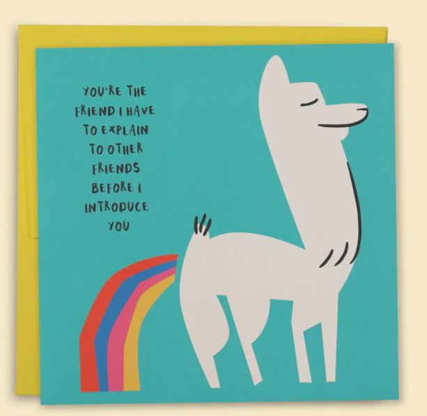 Blue Dog Posters offers a greeting card named "You're The Friend I Have To Explain Greeting Card," featuring a whimsical drawing of a llama farting a rainbow. The teal card, adorned with black text stating, "You're the friend I have to explain to other friends before I introduce you," comes with a bespoke envelope made from recycled paper. A yellow envelope can be seen in the background.