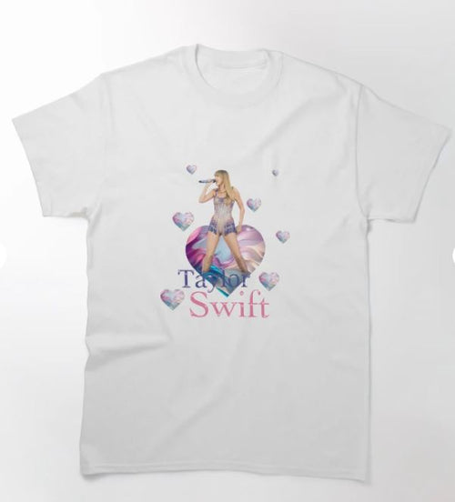 Introducing the Taylor Swift T-shirt WHT LGE by Blue Dog Posters: A stylish white T-shirt showcasing an image of Taylor Swift holding a microphone, surrounded by heart graphics. The text "Taylor Swift" is printed below the image in colorful letters. Available in multiple sizes, this T-shirt proudly supports artists with every wear.