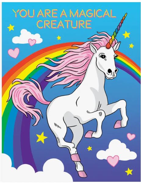 An illustration of a white unicorn with a rainbow-colored horn and pink mane, prancing amid a rainbow and clouds. The background features a blue sky adorned with stars and pink heart shapes. At the top, "YOU ARE A MAGICAL CREATURE" is written in bold orange letters, making it perfect for the Magical Creature Birthday Card by Blue Dog Posters, complete with a matching envelope.