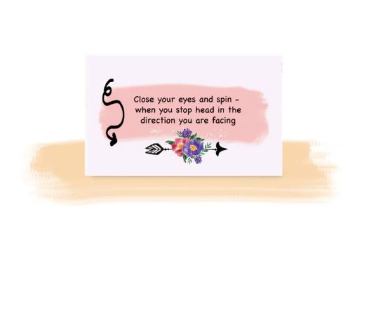 The "Getting Lost Cards - Walkers Edition" from Blue Dog Posters includes a card with a soft pink background, featuring black text that reads, "Close your eyes and spin - when you stop head in the direction you are facing." Below the text is an illustration of a black arrow adorned with a vibrant cluster of colorful flowers, ideal for those who enjoy exploring on foot.