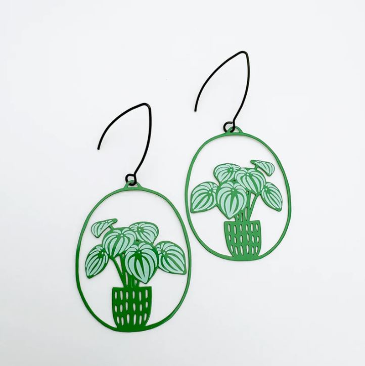 The Watermelon Peperomia plant Denz Earrings by Blue Dog Posters feature two earrings with green metal frames, depicting potted plants with striped leaves. They boast an intricately hand-drawn style and have thin black hooks against a plain white background.