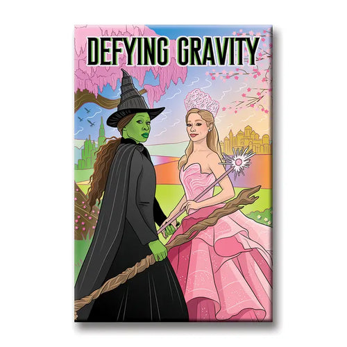 Blue Dog Posters' Wicked Defying Gravity Magnet features two women—one in a black witch costume with green skin and hat, the other in a pink dress with a crown and wand—against a colorful background with "DEFYING GRAVITY" at the top.
