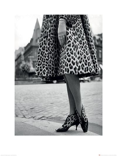 The black and white photograph, titled *Time Life - Dior Leopard Print* by MEZ, captures the lower half of a person standing on a cobblestone street, wearing a leopard print coat and matching high-heeled shoes. The individual also sports a single white glove on their left hand. This striking piece from our Contemporary Art Collection is perfect for any Photographic Art Print enthusiast.