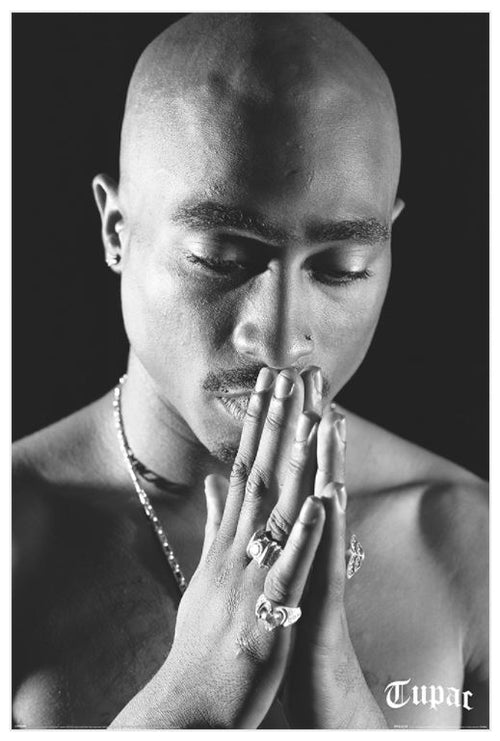 Black and white image of a shirtless person with a shaved head, eyes closed, and hands pressed together in a prayer pose. Adorned with rings and a necklace, the word "Tupac" appears in the bottom right corner. Tupac - praying by MUS 022 is the perfect addition to any music collection or as a hip hop poster on premium 150gsm gloss paper.