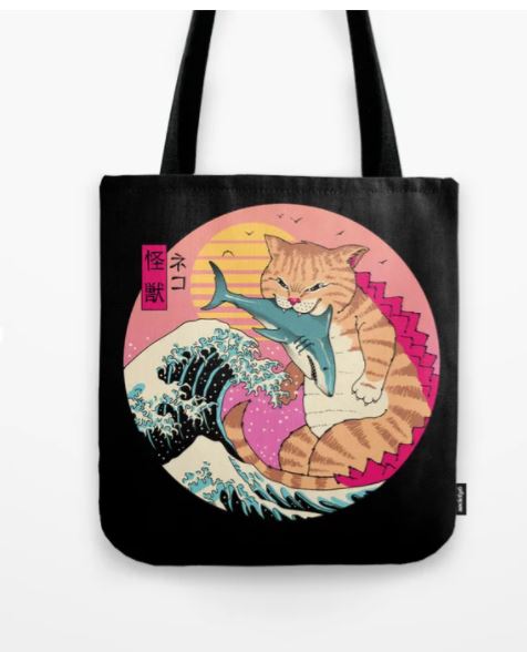 Introducing the Tote Bag 40x40cm Neko Wave Kaiju by Blue Dog Posters: A black tote bag adorned with a vibrant sublimation-printed illustration by Vincent Trinidad, showcasing a large orange tabby cat playfully biting a blue shark. The backdrop features stylized ocean waves and a stunning pink and yellow sunset, complete with Japanese characters near the cat's head.