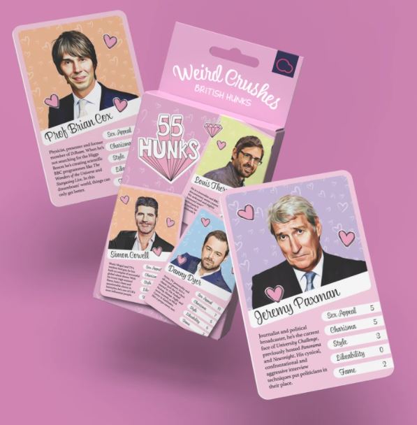 A card collection titled "Bubblegum Stuff British Hunks Card Game" by Blue Dog Posters is displayed. The image shows four cards featuring various men, one of them labeled "Jeremy Paxman." This fun game rates qualities such as sex appeal, charisma, and friendliness. Perfect for the Cool Gifts Collection, the cards have a pink theme.