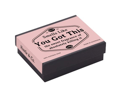 A rectangular pink and black box of goat’s milk soap labeled "You Got This" and "the sweet fragrance of absolutely killing it." The box also states "Hustle & Co." on the side and highlights its 100% natural skincare, with the product proudly Australian made by Blue Dog Posters.