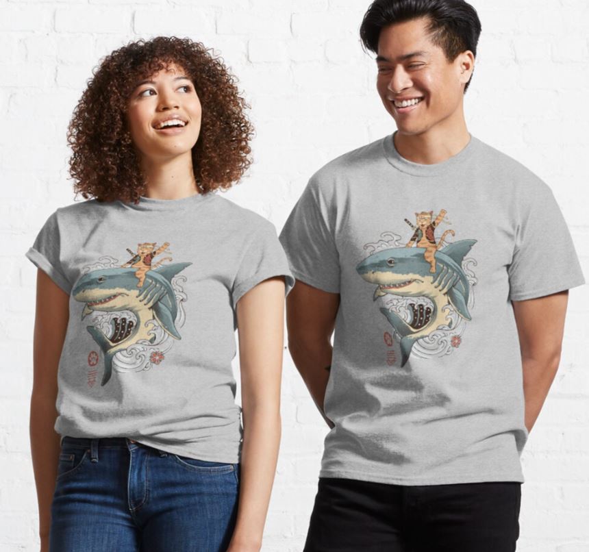 Two people wearing matching Catana Shark T-shirts Grey LGE by Blue Dog Posters smile at each other. Their shirts, a piece of unique artist merchandise, feature an illustration of a cat riding a shark. The cat holds a fishing rod with a fish at the end, and a pirate ship is visible in the background. Both stand against a white, textured wall.