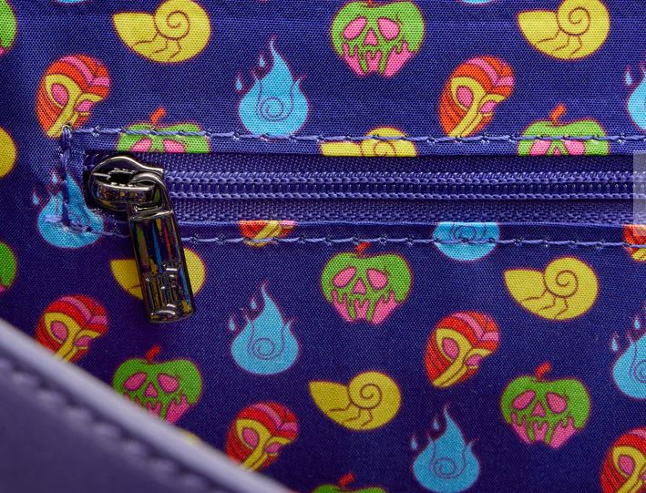 A close-up of the vibrant fabric pattern from the Disney Villains In the Dark Crossbody by Blue Dog Posters showcases skull-shaped apples, blue flames, and striped snails. The design features a prominent zipper with a metal pull tab on a rich purple background, capturing the enchanting essence of this crossbody bag.