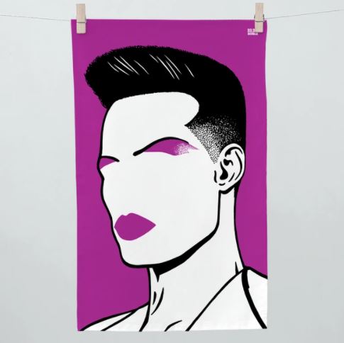 Illustration of a person with short hair styled upward, against a bright magenta background. The facial features are minimalistic, with bold magenta eyeshadow and lipstick. The image, reminiscent of the vibrant *Rock and Pop Icons Tea Towel Grace Jones* by *Blue Dog Posters*, is hanging on a clothesline by two clothespins in the kitchen.