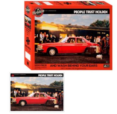 The Holden Wash Behind Ears 1000Pc Puzzle by Blue Dog Posters showcases an image of a red 1977 Holden HZ Kingswood parked in front of a train with passengers. This officially licensed jigsaw puzzle, part of the Giftware Collection, features a vibrant red and yellow theme with "People Trust Holden" and "And Wash Behind Your Ears" on the front.