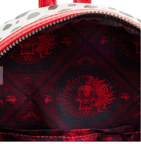 An open 101 Dalmatians Cruella Mini Backpack by Blue Dog Posters, showcasing a red and black interior adorned with an angry, fiery clown face pattern. The exterior is partially visible, featuring the iconic Disney Villains Scene with white and black spots reminiscent of the classic design, complete with a partially opened red zipper.