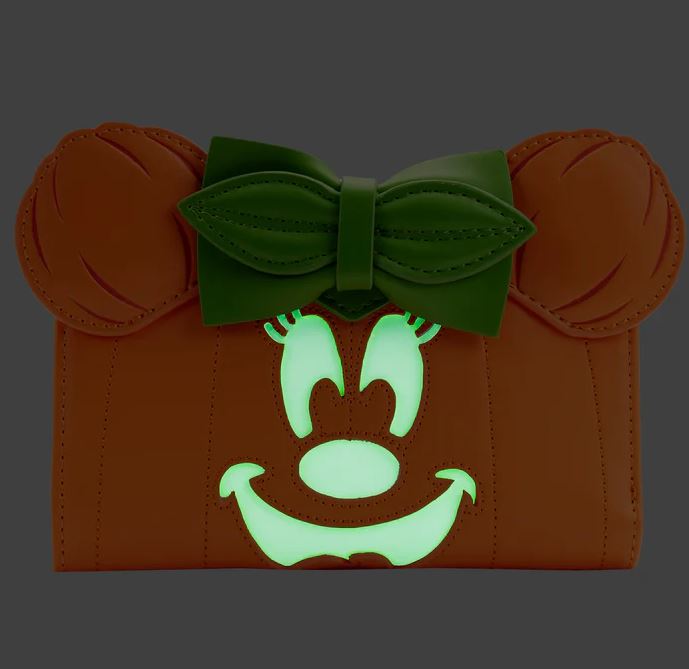 A Disney Minnie Pumpkin Face Flap Purse by Blue Dog Posters, beautifully crafted from vegan leather, designed to look like a cartoon character's face. It features large, glowing white eyes, a smiling mouth with green accents, and a green bow on top—perfect as a whimsical Halloween accessory.