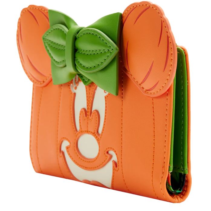 The Disney Minnie Pumpkin Face Flap Purse by Blue Dog Posters is a delightful orange wallet adorned with a whimsical design, including a green bow and large, cartoonish orange ears on top. Crafted from vegan leather, the front features a playful stitched face that resembles Minnie Pumpkin with a smiling expression and reveals a green interior visible from the side—making it an ideal Halloween accessory.
