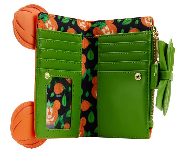 The Blue Dog Posters Disney Minnie Pumpkin Face Flap Purse is a green Halloween accessory with orange pumpkin-shaped ears. Opening it reveals a vegan leather wallet interior adorned with a decorative pumpkin and leaf print pattern, card slots, a clear ID window, and a zippered compartment. A charming bow detail near the opening completes the look.