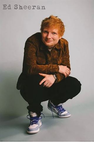 A person with reddish hair squats while smiling, dressed in a brown shirt, black pants, and white sneakers with blue laces. The text "Ed Sheeran" appears in the upper left corner against a plain background. This item is part of the MUS 169 brand and makes a perfect addition to any Music Collection or as a Pop Poster for fans.
