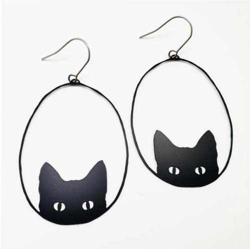 The Denz Cat Black Earrings by Blue Dog Posters are black cat-themed and handmade in Noosa. They showcase an outline of a cat’s head with pointed ears and white eyes on a simple, minimalist white background. Crafted from recycled stainless steel, these lightweight statement earrings are framed in oval wire hoops with hooks for wearing.