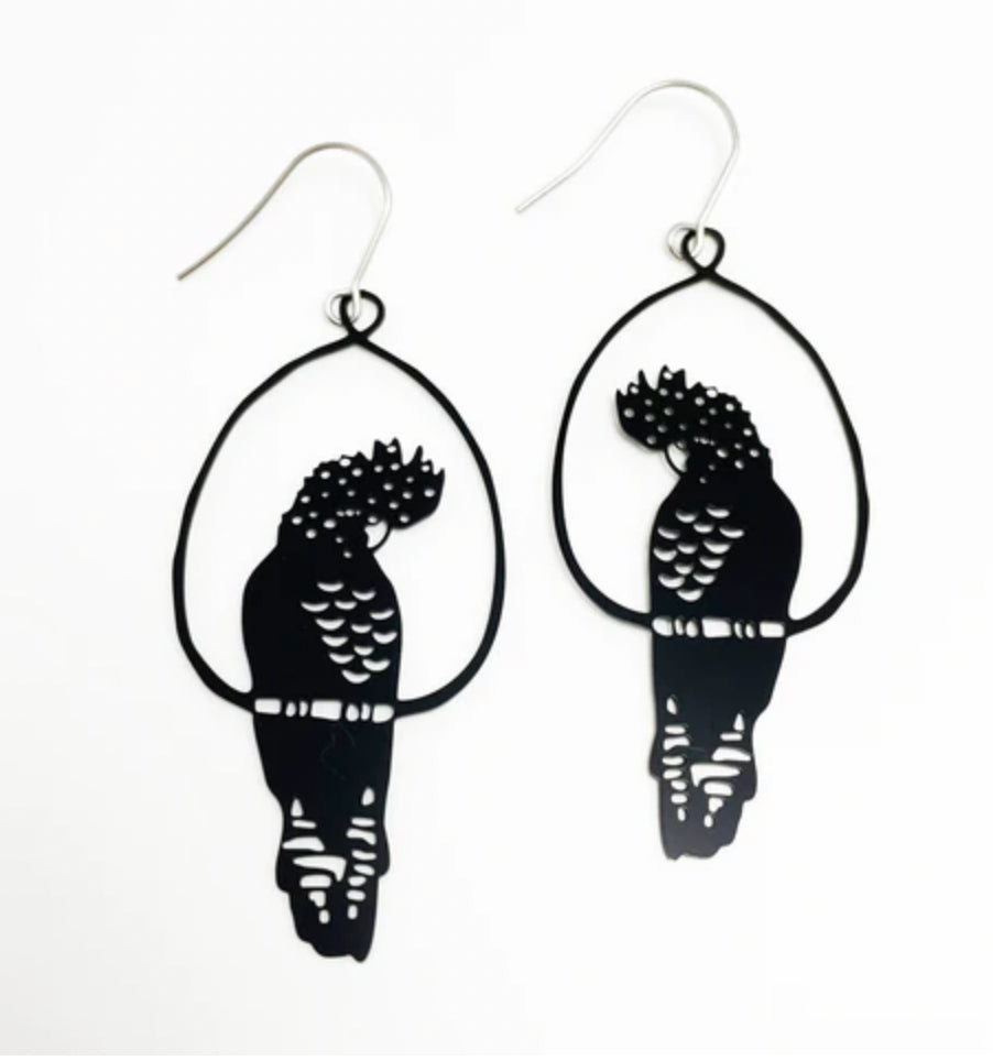 The Denz Cockatoo Black Earrings by Blue Dog Posters are a pair of handcrafted earrings from Noosa, shaped like birds perched in oval frames. Featuring intricate cutouts that highlight the details of the feathers and body, these super lightweight statement pieces are crafted from recycled stainless steel and come with simple fishhook wire closures.