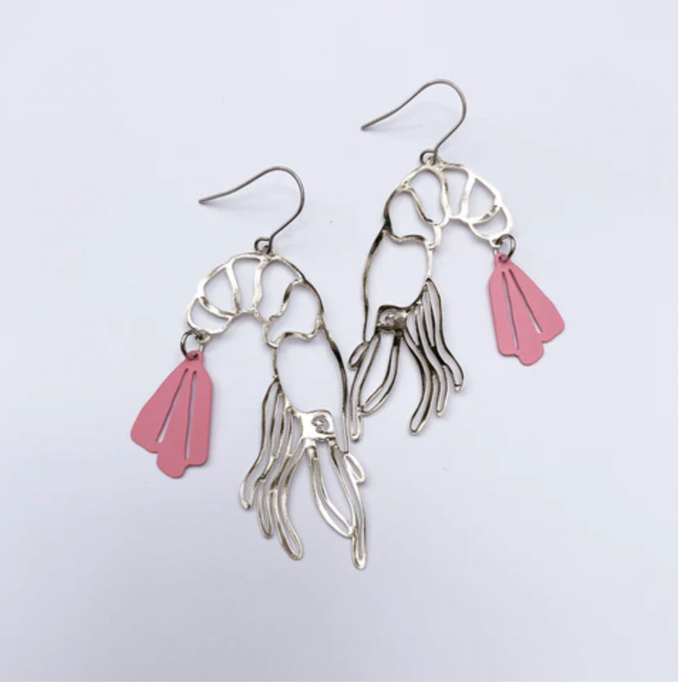 Introducing the Denz Prawn Dangles Pink Earrings by Blue Dog Posters. These handcrafted earrings from Noosa are made of recycled stainless steel and feature a skeletal shrimp design with two delicate pink enameled fins hanging from each piece. Lightweight and elegant, these statement earrings come with simple hooks crafted from the same metal as the shrimp shapes.