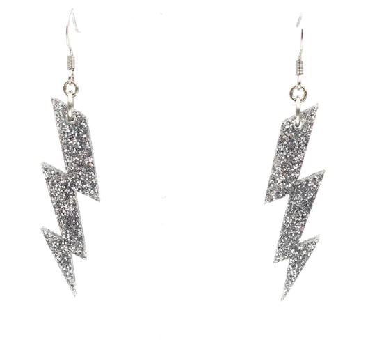 Introducing the Haus of Dizzy Silver Glitter Bolt Earrings by Blue Dog Posters, a dazzling pair of dangling accessories shaped like lightning bolts and covered in silver glitter. These earrings feature hooks for pierced ears and celebrate Indigenous culture with their striking design.