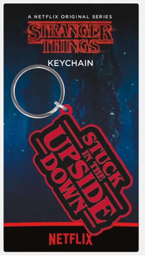 A Stranger Things Rubber Key Chain - Stuck with a black and red design featuring the text "Stuck in the Upside Down" hangs on a card themed with the "Stranger Things" Netflix series. Part of our Cool Gifts Collection, the card has series branding at the top and the word "Keychain" below it. Brought to you by Blue Dog Posters.