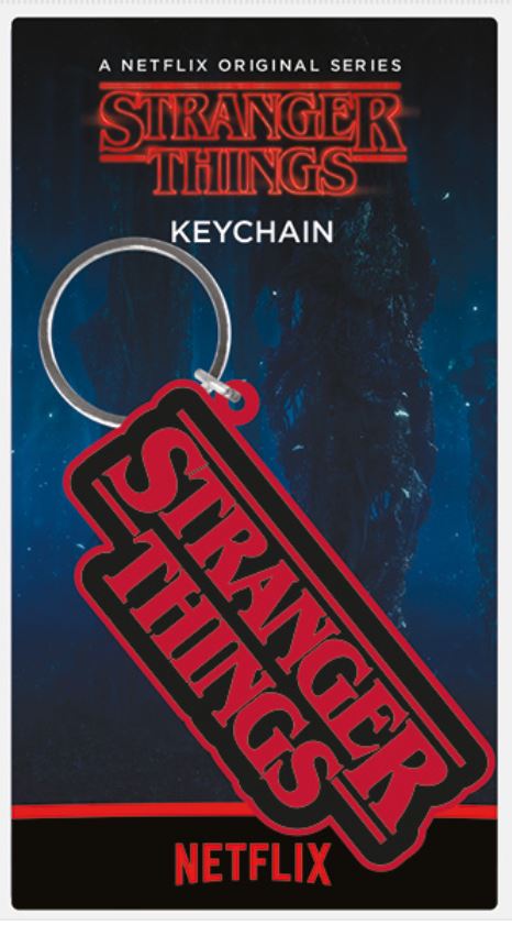 A keyring featuring the "Stranger Things" logo in red text on a black background is displayed. The packaging shows the "Stranger Things" title and a backdrop of a dark, eerie forest. It is labeled as "A Netflix Original Series." Perfect addition to any Cool Gifts collection, with the Netflix logo at the bottom. Introducing the Stranger Things Rubber Key Chain by Blue Dog Posters.