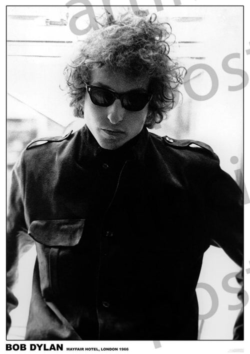A black-and-white photograph captures a person with curly hair wearing dark sunglasses and a high-collared jacket. The person stands against a light background in the Mayfair Hotel, London, 1966. Text at the bottom reads "Bob Dylan Savoy Hotel 1967," perfect for any Music Collection Poster on premium 150gsm gloss paper by MUS 348.