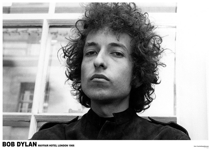 A black-and-white photograph of a person with curly hair, looking directly at the camera with a neutral expression. They are standing indoors, in front of a window. The bottom text reads: "BOB DYLAN MAYFAIR HOTEL LONDON 1966." This premium 150gsm gloss paper music collection poster captures an iconic moment by Bob Dylan from MUS 156.