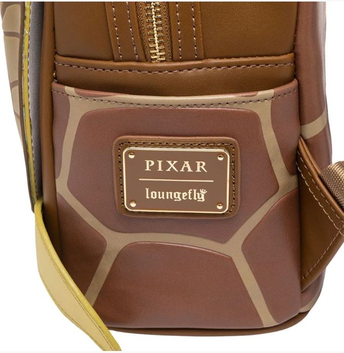 Close-up of a brown Blue Dog Posters faux leather mini backpack with beige and tan geometric designs. This Finding Nemo Crush Mini Backpack features a gold-colored metal logo plate with the text "PIXAR" above and "loungefly" below. The stitching and zipper details are visible.