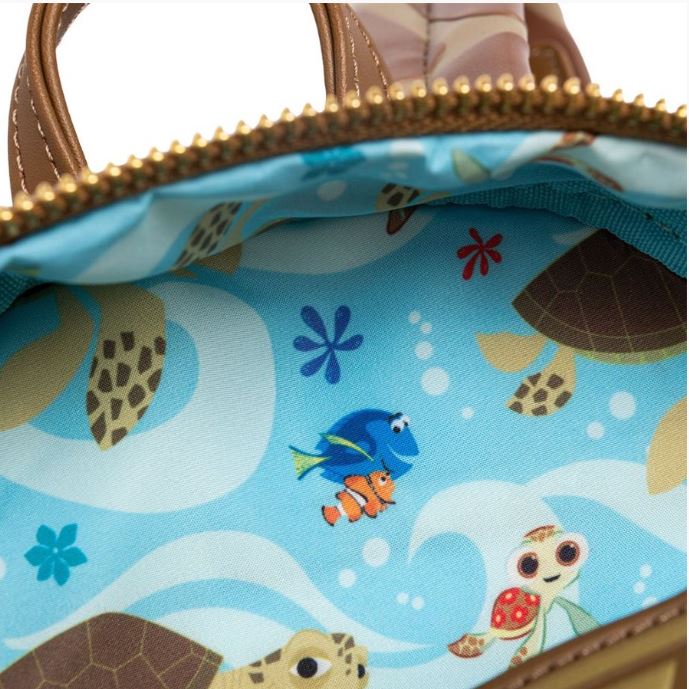 The image showcases the interior of the Finding Nemo Crush Mini Backpack by Blue Dog Posters, revealing a vibrant lining adorned with sea creature illustrations. Among the creatures depicted are turtles, a blue fish, a clownfish similar to characters from Finding Nemo, and a small brown fish, all swimming against a blue wavy background embellished with blue flowers and bubbles.