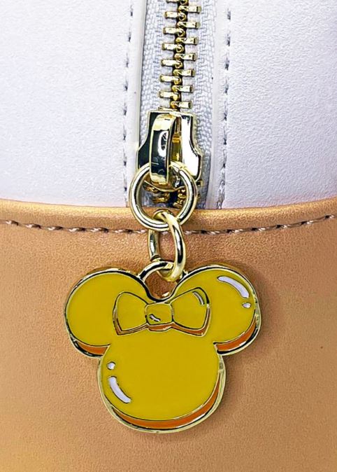 This Blue Dog Posters’ Disney Minnie Ice Cream Backpack features a zipper adorned with a golden-yellow charm shaped like Minnie Mouse's head, complete with a small bowtie. The backpack showcases a white and peach two-toned background.