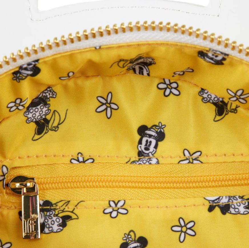 A close-up shot of a yellow, vegan leather fabric adorned with white flowers and black-and-white images of Minnie Mouse in various poses. The Disney Minnie Mouse Daisies Crossbody Bag by Blue Dog Posters, an officially licensed Disney accessory, features a golden zipper at the bottom of the image.