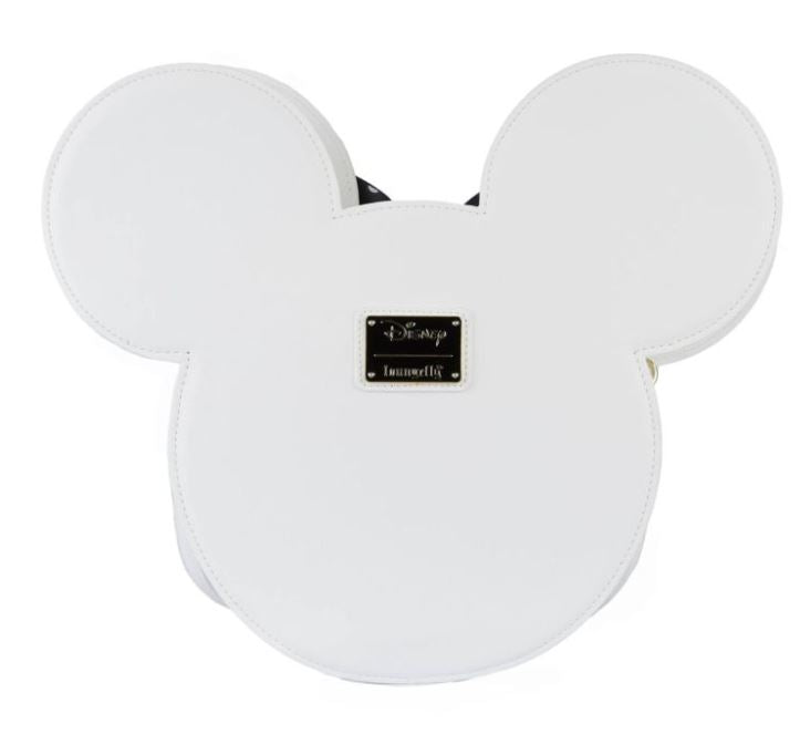 A crossbody bag in the shape of Minnie Mouse's head, made from vegan leather, featuring a small black rectangular plaque with the "Blue Dog Posters" logo embossed in gold. The minimalist design captures the iconic silhouette with a touch of daisy detailing and is officially licensed by Disney.